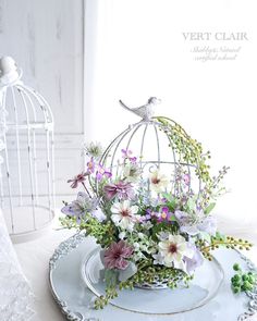 a birdcage filled with flowers sitting on top of a plate