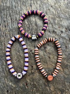 three bracelets with skulls and colorful beads on top of a stone surface next to each other