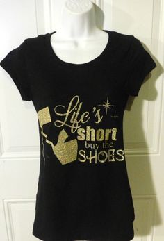 "Celebrate your Shoe Fever with this fun and fashionable tee. Shirt is inscribed, \"Life's short, buy the shoes!\" in glittered script. Black, crewneck shirt with short sleeves. Cotton/Spandex. Available in sizes: S-XL." Black Crewneck, Crew Neck Shirt, Graphic Tees Women, Cotton Spandex, Womens Clothing Tops, Tee Shirt, Diva, Graphic Tees, Short Sleeves