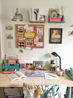 a desk with many books and pictures on the wall