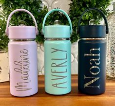 three water bottles sitting on top of a wooden table