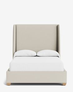 an upholstered bed with two pillows on it