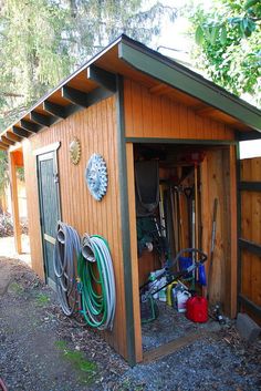 an outhouse with many tools in it and some hoses hanging from the roof