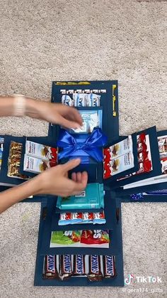 a person opening a box with snacks on the floor next to other boxes and packages