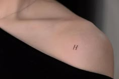 a woman's shoulder with the letter h tattooed on her left arm and upper half