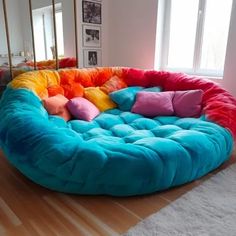 a large round couch with colorful pillows on it's sides in a living room