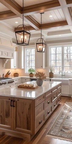 a large kitchen with an island in the middle and two hanging lights above it, along with hardwood flooring