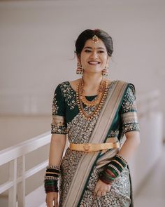 a woman in a green and gold sari smiles at the camera while standing on a balcony