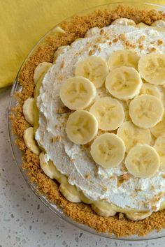 a pie topped with bananas on top of a table next to a yellow banana peel