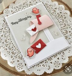 a close up of a greeting card on a doily with an envelope and two hearts