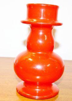 an orange vase sitting on top of a wooden table