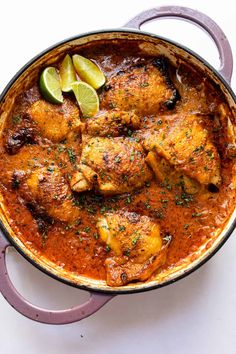 chicken curry in a pan with limes on the side