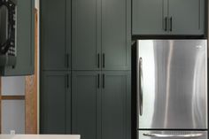 a stainless steel refrigerator freezer sitting in a kitchen next to green cabinets and cupboards