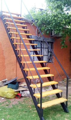 a set of stairs with yellow steps next to a red wall and trash bag on the ground