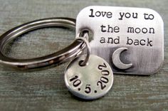 a couple of key chains that are on top of a wooden table with the words love you to the moon and back