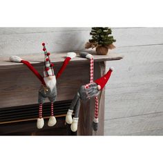 two knitted elves hanging from a mantel