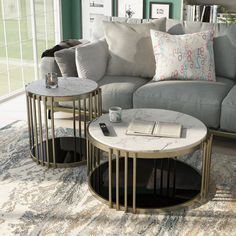 two tables sitting on top of a rug in front of a couch and coffee table