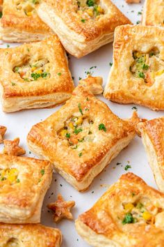 many small pieces of food on a white surface with parsley sprinkled around them