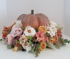 an arrangement of flowers and pumpkins on a table