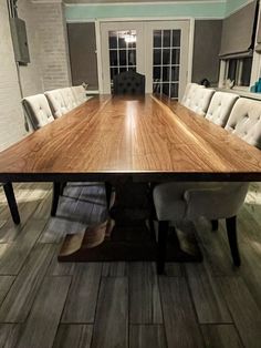 a large wooden table sitting in the middle of a room with white chairs around it