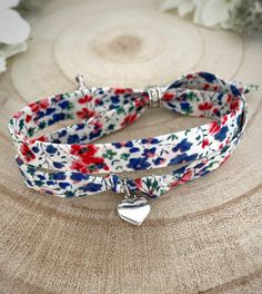 a white and blue flowered bracelet with a heart charm on it's side