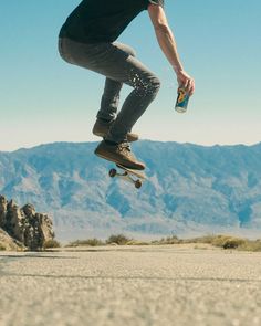 a skateboarder is doing a trick in the air with mountains in the background