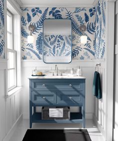 a bathroom with blue and white wallpaper and a mirror above the sink, along with a rug on the floor