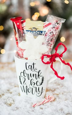 a cup filled with candy and marshmallows on top of snow covered ground