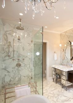 a bathroom with a tub, chandelier and two sinks inside of it next to a walk in shower