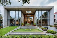 the entrance to a modern house with large windows and plants on the front lawn area