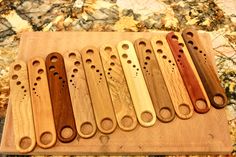 six wooden utensils are lined up on a cutting board with holes in them