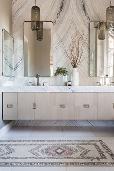 a bathroom with marble counter tops and two mirrors on the wall next to a rug