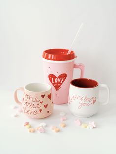 three coffee mugs with hearts on them and one has a straw in the cup