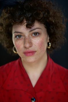 a woman with freckled hair wearing a red shirt