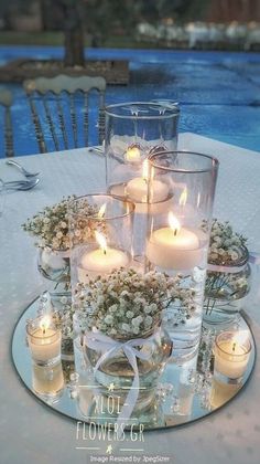 a table with candles and flowers on it next to a swimming pool in the background