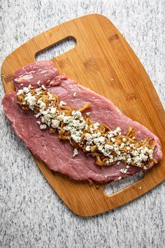 a piece of meat sitting on top of a wooden cutting board