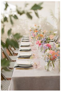 a long table set with place settings and flowers