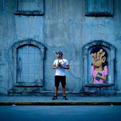 a man standing in front of a building with graffiti on it