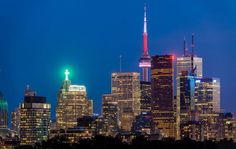 the city skyline is lit up in red, white and blue at night with skyscrapers