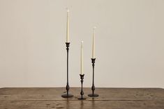 two black candlesticks sitting on top of a wooden table next to each other