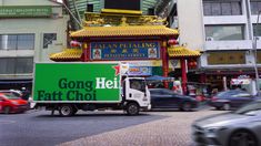 a truck is driving down the street in front of a chinese restaurant and other buildings