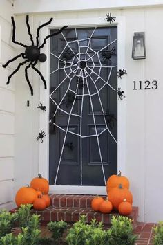 a front door decorated with pumpkins and spider web