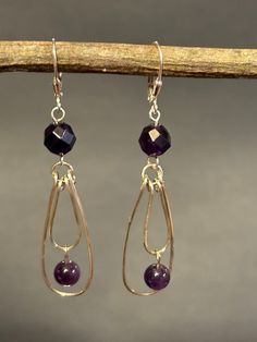 Artisan designed and handcrafted one of a kind sterling silver hoops with around amethyst amethyst's. The dangle is a 6 mm amethyst. The 8 mm faceted amethyst connects the hoops and the earring wire.  Minimalist designed shiny with faceted beads reflecting the light. This would make a great gift.  Overall length is 2 1/4 inches long including the sterling silver leverbacks earring wire. The width is 1/2 inch wide and the drop length is 1 3/4 inches  long. Minimal Chandelier, Handmade Amethyst Purple Earrings, Purple Artisan Earrings With Ear Wire, Wire Wrapped Amethyst Drop Earrings, Handmade Amethyst Chandelier Earrings, Amethyst Chandelier, Amethyst Hoop Earrings With Ear Wire, Gift, Chandelier Minimalist, Earring Wire