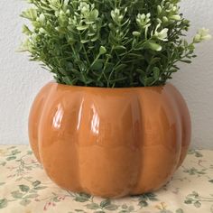 an orange pumpkin shaped planter sitting on top of a table