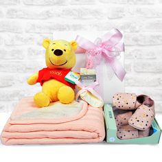 a teddy bear sitting on top of a pile of blankets next to baby booties