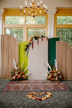 a wedding ceremony setup with flowers and greenery on the floor in front of an open window