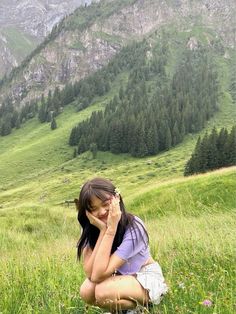 a woman sitting in the grass with her hands on her face