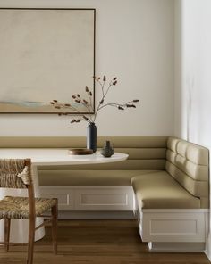 a white table and bench in a room with a painting on the wall behind it