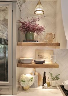 a kitchen with open shelving and flowers on the counter