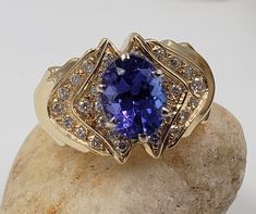 Title: Oval Tanzanite and Diamonds in 14 Kt Yellow Gold Ring Size 6. 1/2 US DesignerUnbranded MaterialYellow Gold 14Kt Stamped Style: Vintage Gemstone Details All measurements are approximate and may vary slightly from the listed dimensions. Diamonds: Cut: Round Diamonds 30 Estimated Size 1.8 mm and 1.5 mm average approximated 0.55 CTW Estimated Color: G-H Clarity: VS Tanzanite: 9.24 mm/7.04 mm/4.22 mm 1.93 CT Estimated Measurements Length/Width/Depth 20.52 mm/12.55 mm/8.47 mm Estimated Total We Unique Oval Gold Gemstones, Collectible Yellow Gold Jewelry With Accent Stones, Oval Tanzanite Gemstones In Yellow Gold, Exquisite Oval Gold Gemstones, Gold Tanzanite Rings With Accent Stones, Formal Gold Gemstones Stamped 14k, Gold Gemstones Stamped 14k Fine Jewelry, Gold Tanzanite Oval Jewelry, Gold Oval Gemstones With Accent Stones